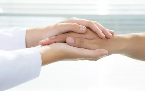 A practitioner clasping a client's hand with two hands.