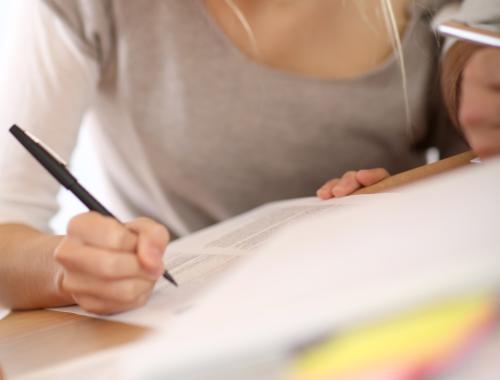 A woman at a desk writing on a printed paper form.