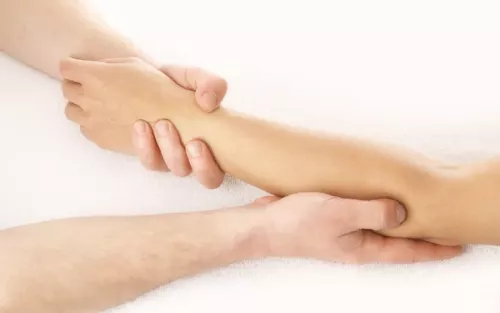 A therapist working gentle with a client's arm and elbow.