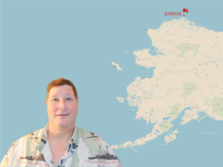 Mark White in front of a map of Alaska showing the small town of Barrow on the remote northern tip.