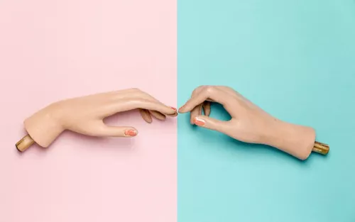 Two mannequin hands reaching out to each other to almost touch fingers.