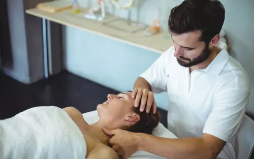 A practitioner gently working on a woman's head and neck area with this fingers and thumbs.