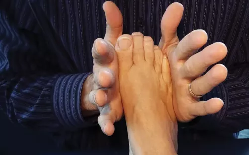 A therapist using two hands to squeeze either size of a client's foot.
