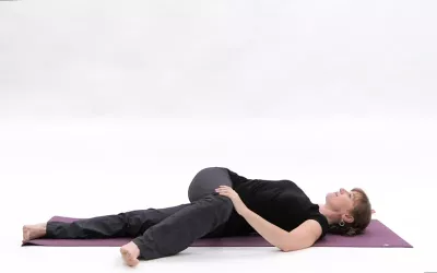 A woman engaging in a supine twist on her right side.