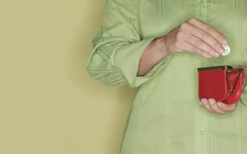 Person in a green blouse reaching into a red coin purse.