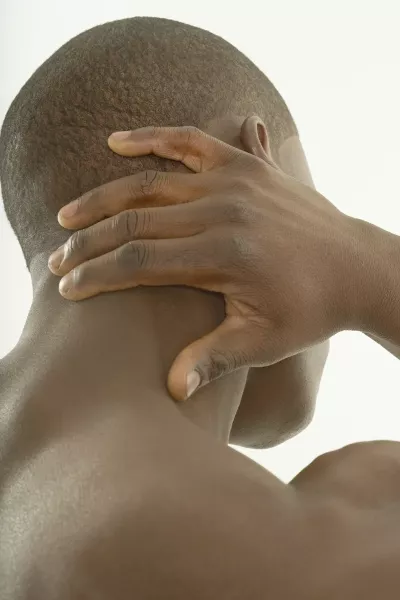 An African American person holding the back of their head and neck.