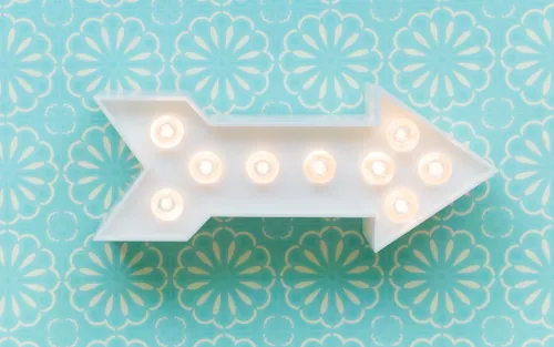 A decorative arrow on a wall lit up with lightbulbs.