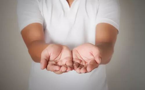 A person in a white uniform holding out two cupped hands.