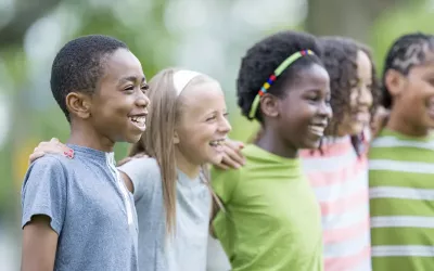 A row of school age children of different ethnicities stand together.