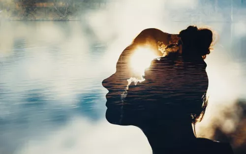 Shadowed outline of a woman breathing over a calm ocean landscape at sunset.