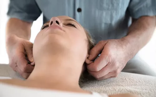 Til Luchau holds a client's earlobes very gently, demonstrating the Vagus Nerve Technique.