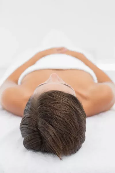 View angled from head to toe of a draped person on a massage table.