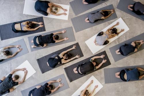 Aerial view of dozens of yogis in child's pose on their mats.