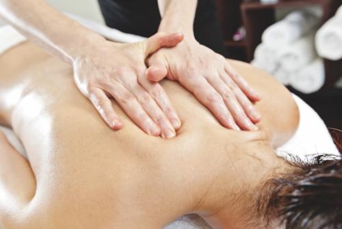 An MT using two hands with light pressure on a client's upper back.