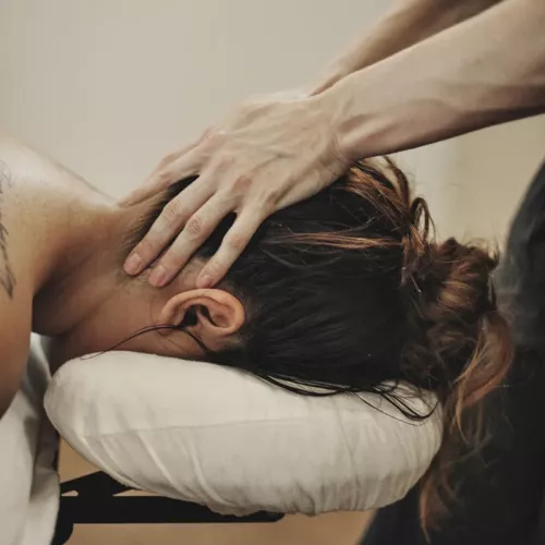 Two hands applying pressure to a woman's upper cervical spine/neck area.