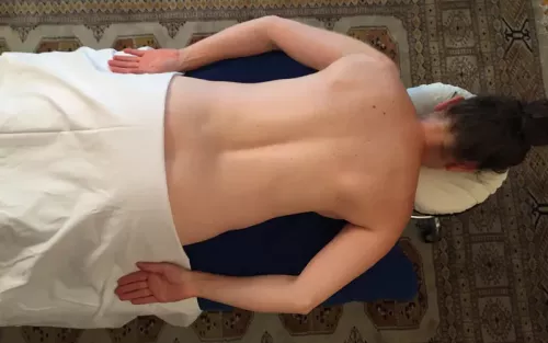 A prone female client with her hands, palms up, by her sides.