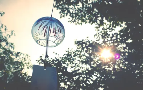 A wind chime made of metal and glass swings outside.