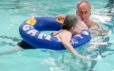 A woman on a floating ring tube, working in the water for therapy alongside the author.