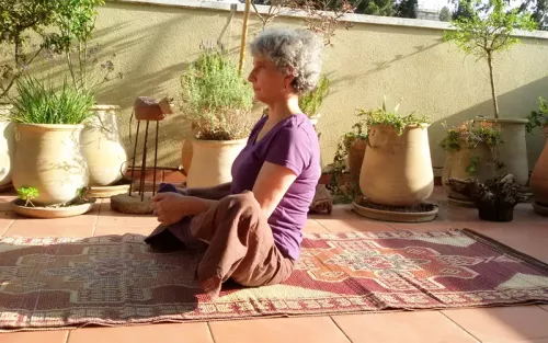 Vered at her home practicing yoga on a rug on an outdoor patio..