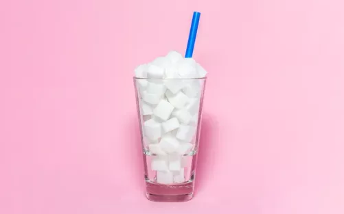 A tall glass full of sugar cubes with a straw sticking out.