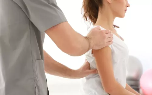 A practitioner gently holds the shoulder and back of a client.