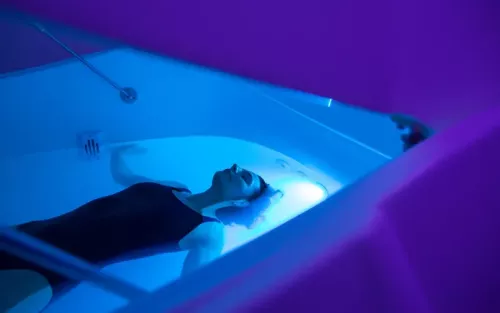 A woman floating face-up inside a large water tank.