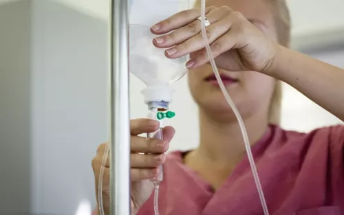 a woman changing out a drip IV.