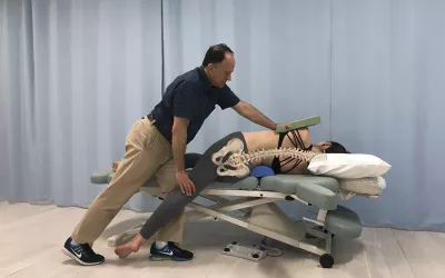 Dr. Joe demonstrates a stretching technique with a client on the table, assisted with bolsters.