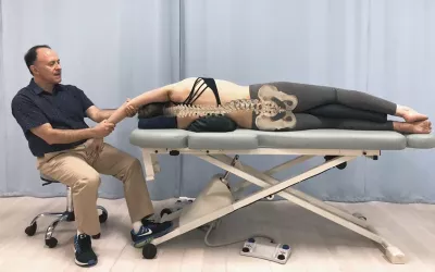 Dr. Joe demonstrates a stretching technique of a client's upper extremity (right arm) while sidelying.