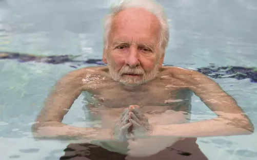 Harold Dull holding his hands in a prayer position, floating calmly in a pool.