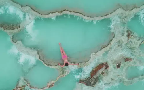 Aerial view of a woman in a swimsuit sitting in an ocean pool.