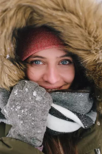 A woman bundled up in winter clothes and a large fur hat.