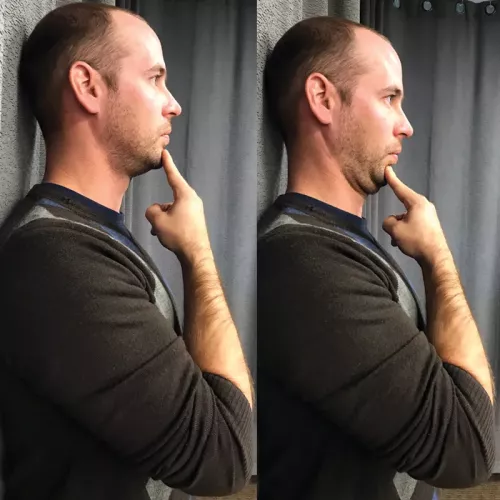 A an with his head flat and neutral up against a wall, tilting his chin downward with his index finger.
