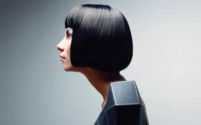 A woman with a short, black bob haircut and a slouched posture.