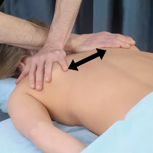 A therapist with arms crossed, working on opposite scalenes on a woman's back.