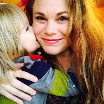 Ashley Hurlburt with her young son who's hugging and kissing her face.