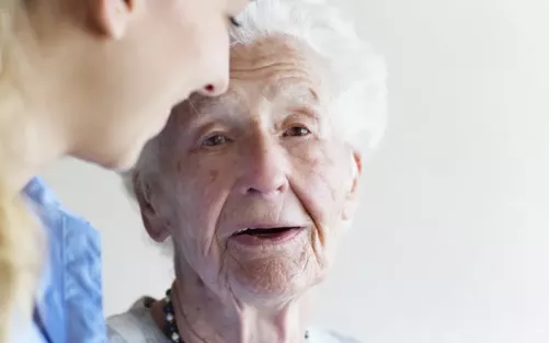 An older woman with no teeth gently smiling.