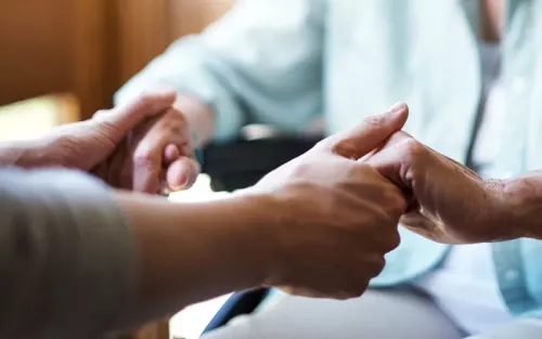 Two older people holding hands together.