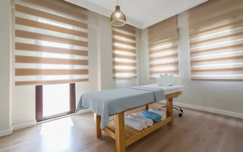 An empty room with a single massage table and light white floors and walls.