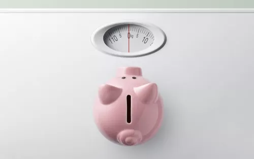 A pink ceramic piggy bank resting on a weight scale.