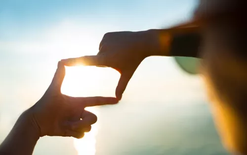 A person making a window frame with the outline of their fingers.