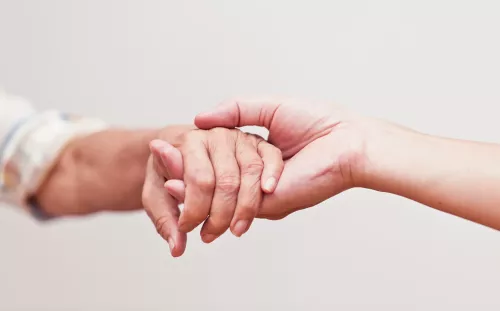 Two hands reach out and clasp each other.