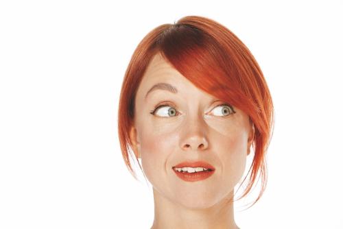 A woman with red hair in an updo turns her head, looking surprised.