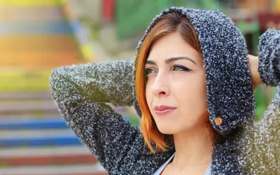 A woman in a fuzzy hoodie gazes forward. 