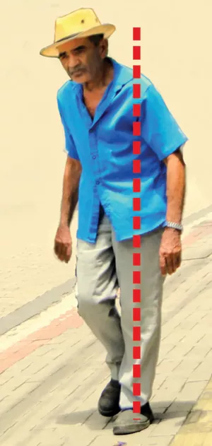 A man in a hat walking in an unbalanced position, leaning to his right side.