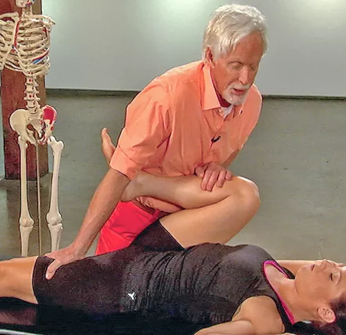 Erik Dalton bending a supine client's leg at the knee, pushing against it.