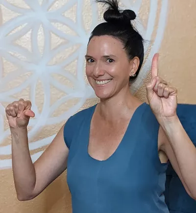 a woman testing her hand-brain coordination by holding up a fist with one and and one finger with another, then alternating the movements.
