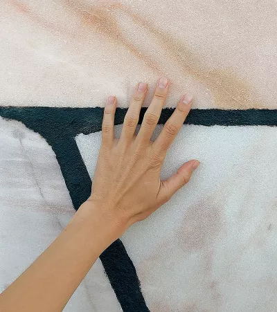 a hand with the palm splayed up against a painted wall.