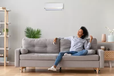a woman with curly dark hair lounges on a couch.