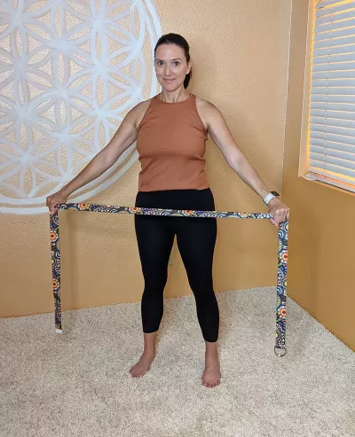 Nicole Reed holding up a strap with both hands to demonstrate a range of motion exercise.